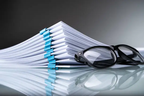 Stacked Documents With Blue Paperclips And Eyeglasses