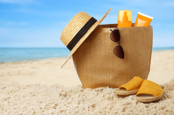 istock Stylish bag with different accessories on sandy beach near ocean 1391809537