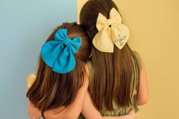 Girls with blue and yellow bows are standing with their backs hugging