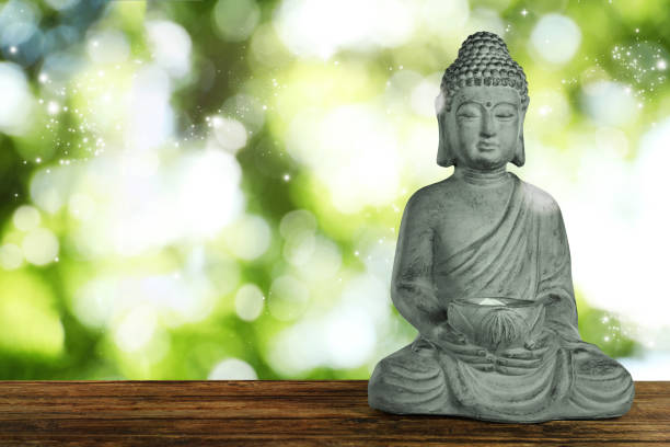 istock Stone Buddha sculpture on wooden table outdoors. Space for text 1391810651
