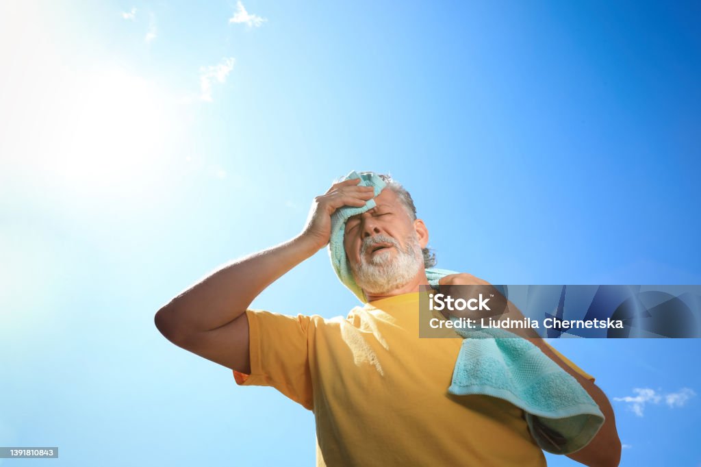 Senior man with towel suffering from heat stroke outdoors, low angle view Heat - Temperature Stock Photo