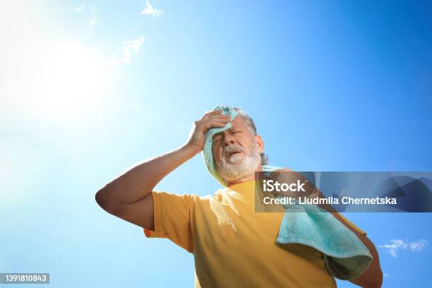 Senior Man With Towel Suffering From Heat Stroke Outdoors Low Angle View Stock Photo - Download Image Now