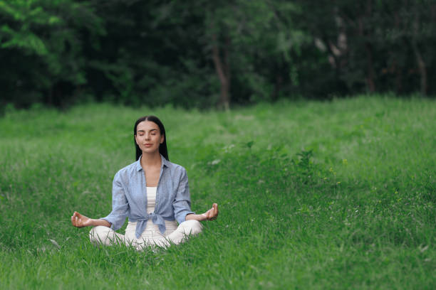 istock Young woman meditating on green grass. Space for text 1391811400
