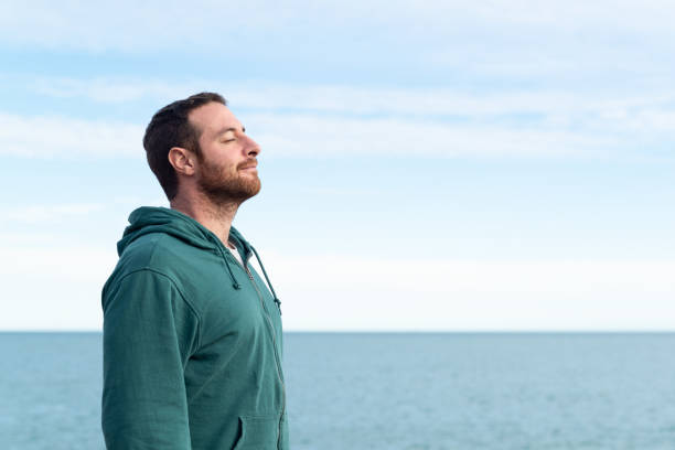 Relaxed man breathing fresh air. Relaxed man breathing fresh air with the sea at the background. inhaling stock pictures, royalty-free photos & images