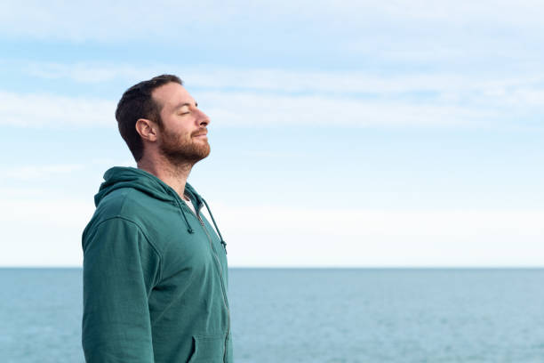 Relaxed man breathing fresh air. Relaxed man breathing fresh air with the sea at the background. mindfulness stock pictures, royalty-free photos & images