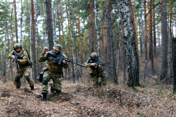 Three mercenaries during a special operation in the forest on the vrezhskaya territory. They move to join the main group after landing behind enemy lines stock photo