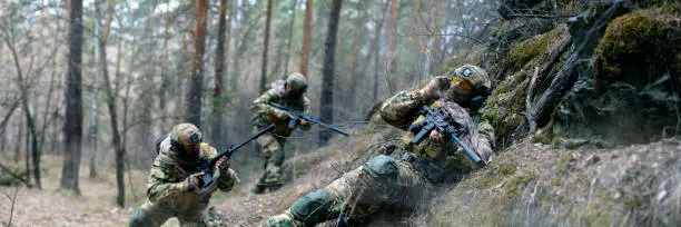 Photo of Three mercenaries during a clash in enemy territory. Special operation in the forest. The soldiers were ambushed