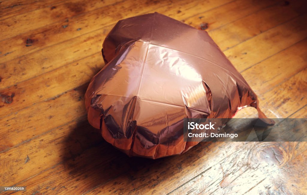 inflatable balloon in the shape of a pink heart, lying on the ground half deflated, as a symbol of lost love or heartbreak. Deflated Stock Photo