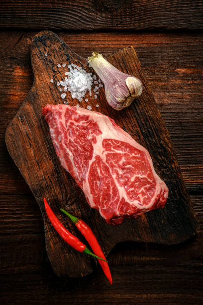 istock Raw Flat Iron beef steak on a wooden Board with red pepper, top view 1391821095