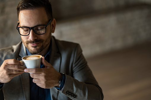 Close-up of happy male entrepreneur drinking coffee on a break in office.