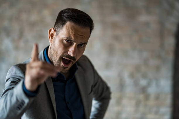 Frustrated businessman screaming of disappointment and looking at camera.