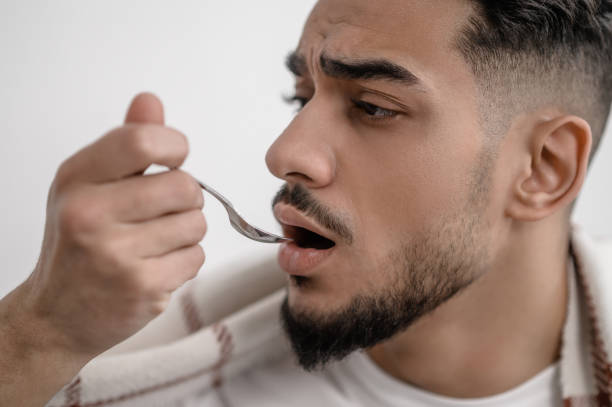 istock A sick man taking a spoon with medicine 1391823511