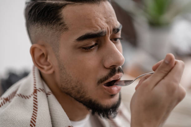 istock A sick man taking a spoon with medicine 1391823560