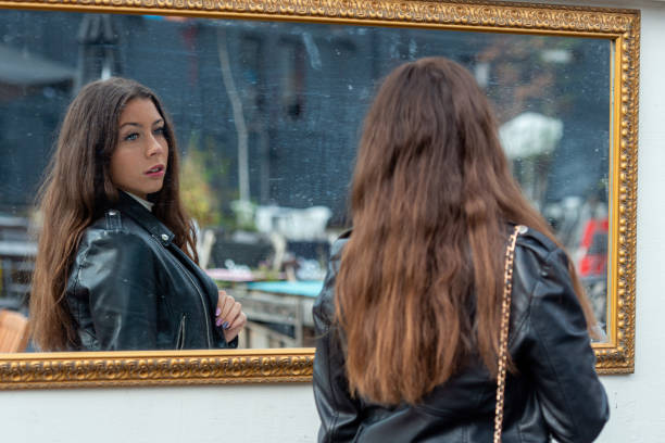 istock A young, positive  woman makes various grimaces and enjoys her reflection in the mirror 1391825835