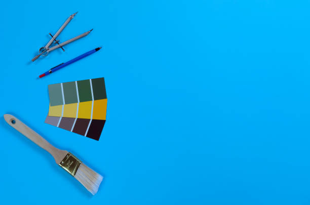 istock Blue desk setting with architect designer tools consisting of mechanical pencil, paint sample cards, paint brush and compass. 1391827653