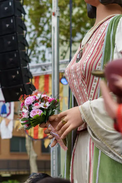 Photo of Giants and big heads. Traditional festival in Badalona, Barcelona, Spain. Detail of hand fence with bouquet of flowers.