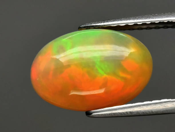 istock Natural gemstone opal in tongs on a gray background 1391832877