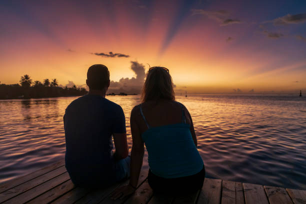istock A man and woman sitting on a pier at sunset. 1391833803