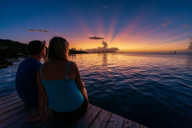 istock A man and woman sitting on a pier at sunset. 1391833817