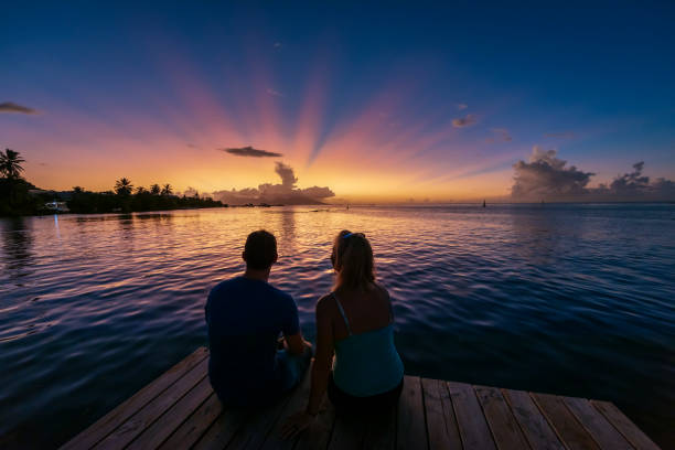 istock A man and woman sitting on a pier at sunset. 1391833827