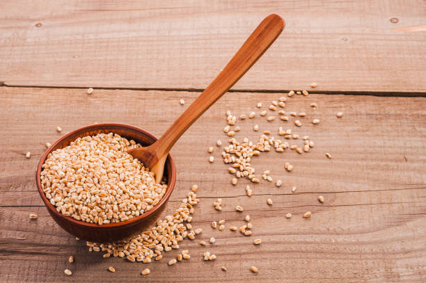 istock Spoon of wheat grain on a wooden background. 1391835026