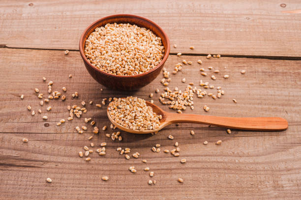 istock Spoon of wheat grain on a wooden background. 1391835028