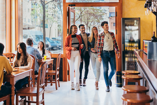 Full shot of a interracial group enters a restaurant