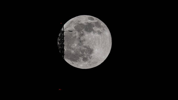 Pink moon scraping TV Tower Stuttgart -Airplane in the moon super full moon behind the Stuttgart TV Tower - the antenna is touching the moon. An airplane is flying across contrail moon on a night sky stock pictures, royalty-free photos & images