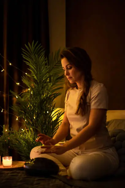 Spiritual yoga woman playing melody on glucophone practice mindfulness harmony balance at bedroom. Yogi female use authentic percussion drum sitting in lotus position relaxing at comfortable home