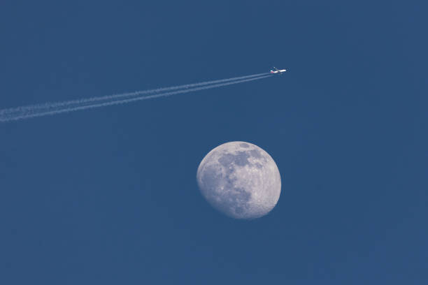 avión que pasa por la luna encerada en el cielo azul - luna creciente fotografías e imágenes de stock