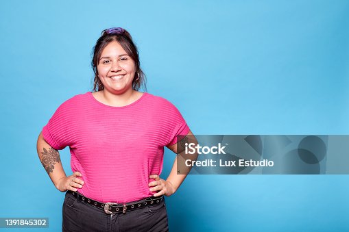 istock Young curvy latina woman smiling looking at camera isolated on turquoise background. Copy space. 1391845302