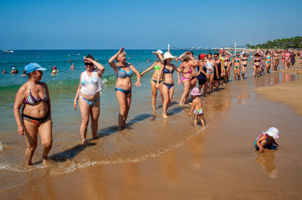 Antalya, Turkey - August 30, 2018 : Middle-aged women do aerobics on the beach while children play in the sand