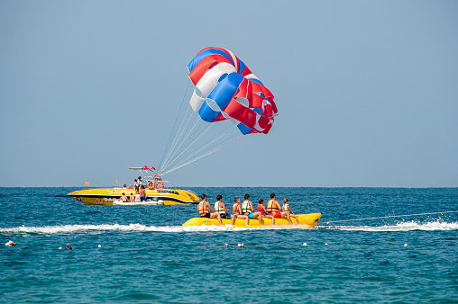 Antalya, Turkey - August 30, 2018 : Tourists getting on a yellow banana boat in the sea and tourists doing parasailing