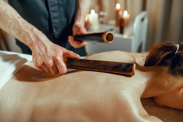 istock Male therapist doing back massage to woman using hollow bamboo canes 1391859766
