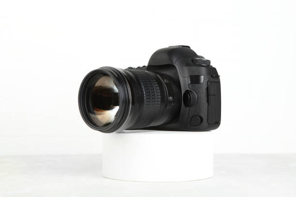 istock Big Black DSLR Digital Camera full frame sensor with lens on gray white cement background. 1391864695