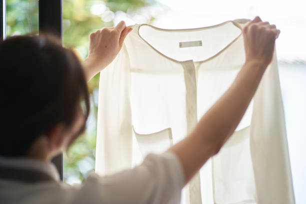 istock Asian woman hanging laundry by the window 1391865723