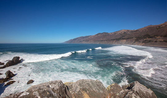 Wave breaking into cove at original Ragged Point peninsula at Big Sur on the Central Coast of California United States
