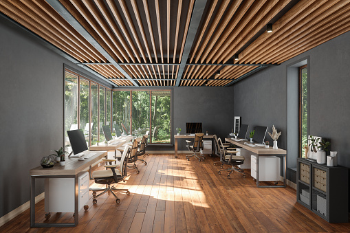Moderno interior de oficina de planta abierta con mesas, sillas de oficina, suelo de parquet y vista al jardín desde la ventana photo