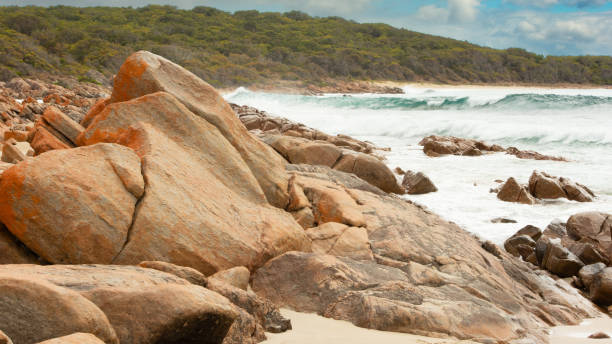istock Slab of orange rock with ocean surf breaking 1391876794