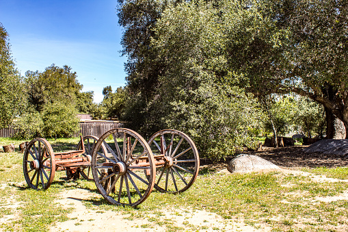 An old piece of farm equipment sits near a farm field in the mountains of San Diego California in spring
