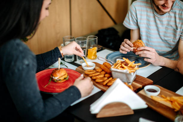 Friends having lunch together in restaurant eating burgers
