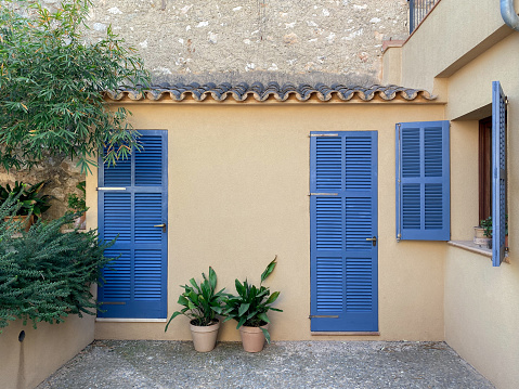 Facade with freshly painted turquoise blue mediterranean shutters