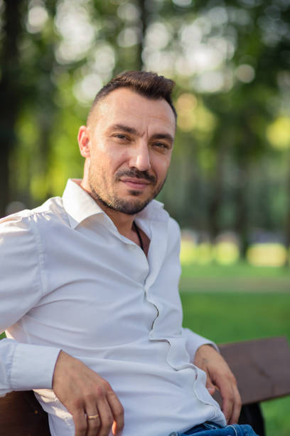 istock A happy business man in a white shirt is resting while sitting on a bench. 1391889685