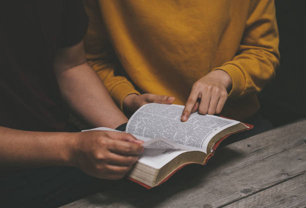 due cristiani seduti attorno a un tavolo di legno con lo studio della bibbia e la preghiera a dio insieme. - bible study foto e immagini stock