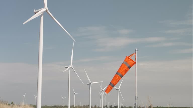 Windmill rotating in Wind Turbine field with orange wind sock , Green energy and Renewable energy concept