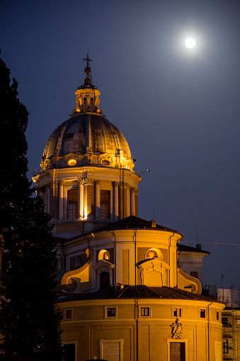 An idyllic night view in the baroque heart of Rome with a bright full moon. In the foreground, the Basilica of Saints Ambrogio and Carlo, along Via dei Corso, in the Piazza di Spagna district. The church, built in 1612 in Baroque style, is dedicated to Saint Ambrose and Saint Charles Borromeo, patrons of Milan. Among the numerous works of art present inside the church is the Chapel of St. Olav of Norway, dedicated to the martyr king who converted to Christianity and was killed in the battle of Stiklestad in 1030. In 1980 the historic center of Rome was declared a World Heritage Site by Unesco. Image in High Definition format.