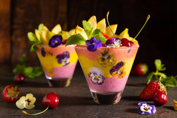 Delicious layered berry and fruit smoothie with edible flowers. Healthy dessert. Clean eating. Delicious layered berry and fruit smoothie with edible flowers. Healthy dessert. Clean eating. starfruit stock pictures, royalty-free photos & images