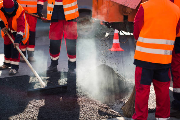 istock Worker leveling fresh asphalt on a road construction site, industrial buildings and teamwork. 1391909620
