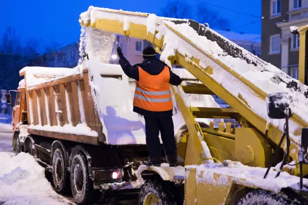 Photo of Claw loader vehicle removes snow from the road. Snow plow machine and snow truck clean the streets of snow in city.