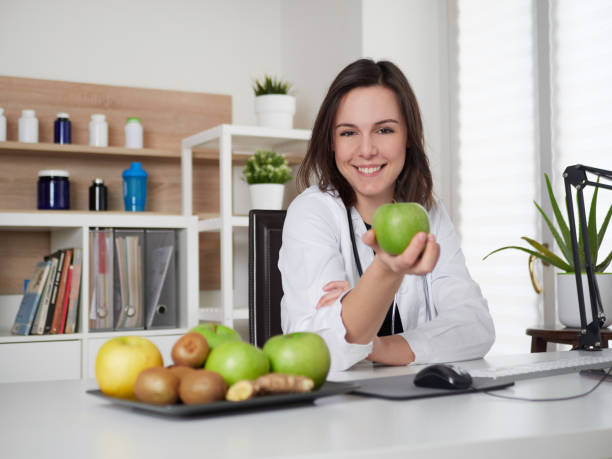 istock Young Female nutritionist holding a green apple 1391914084